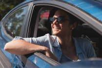 Schöne Frau lächelt, während sie im Auto sitzt — Stockfoto