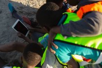 Вид сзади на детей с помощью цифрового планшета в земле — стоковое фото