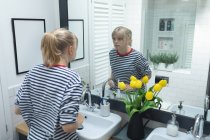 Красивая женщина смотрит в зеркало в ванной комнате — стоковое фото