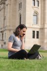 Mulher usando laptop enquanto fala no celular no parque — Fotografia de Stock