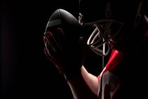 Primo piano del giocatore di football americano in piedi con casco da rugby e palla — Foto stock