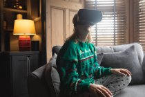 Женщина с гарнитурой виртуальной реальности на диване дома — стоковое фото