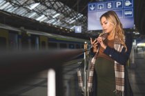 Красива вагітна жінка використовує мобільний телефон на залізничній станції — стокове фото