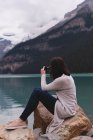 Вид збоку жінки, що натискає фотографії з камерою біля озера — стокове фото