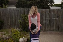 Мать обнимает свою дочь на заднем дворе — стоковое фото