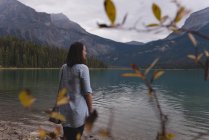 Задумчивая женщина, стоящая у озера — стоковое фото