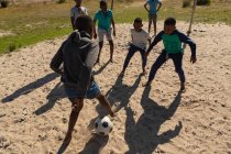 Crianças jogando futebol no chão em um dia ensolarado — Fotografia de Stock