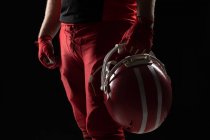Sezione centrale del giocatore di football americano in piedi con casco sullo sfondo nero — Foto stock