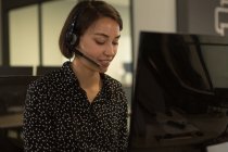 Ejecutivo de servicio al cliente hablando en auriculares en el escritorio en la oficina - foto de stock