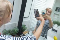 Крупный план женщины, делающей селфи на мобильном телефоне в ванной комнате — стоковое фото
