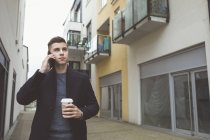 Homem elegante usando telefone celular enquanto toma café — Fotografia de Stock