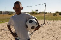 Мальчик держит футбол в земле в солнечный день — стоковое фото