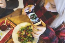Overhead of woman taking photo of food in cafe — Stock Photo