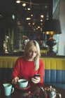 Женщина, пользующаяся мобильным телефоном во время кофе в кафе — стоковое фото