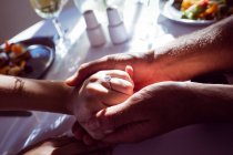 Close-up of couple holding hands in restaurant — Stock Photo