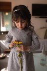 Innocent girl holding a flower at home — Stock Photo