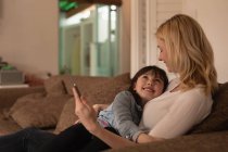 Mère et fille utilisant une tablette numérique dans le salon à la maison — Photo de stock