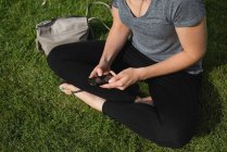 Frau benutzt Handy an einem sonnigen Tag im Park — Stockfoto