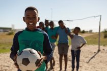 Junge hält Fußball an einem sonnigen Tag in der Erde — Stockfoto