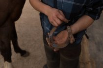 Sezione media della donna che tiene il ferro di cavallo nella stalla — Foto stock