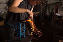 Aufmerksame Metallschmiederin formt Hufeisen in Fabrik — Stockfoto