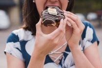 Крупним планом жінка має пончик в місті — стокове фото
