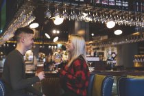 Heureux couple prenant des boissons au comptoir du bar — Photo de stock