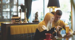 Молодая пара обсуждает по мобильному телефону в ресторане — стоковое фото