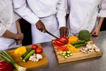 Mid section of chef chopping vegetable in kitchen — Stock Photo