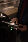 Seção média de homem de negócios usando tablet digital ao carregar carro elétrico — Fotografia de Stock