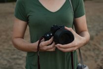 Seção média de mulher segurando câmera na praia — Fotografia de Stock
