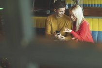 Пара обговорює на мобільному телефоні в кафе — стокове фото