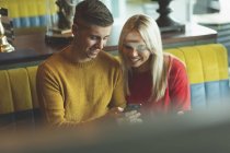 Пара смотрит на мобильный телефон в кафе — стоковое фото