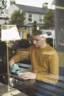 Jeune homme versant du lait dans une tasse de café à la cafétéria — Photo de stock