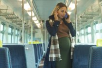 Вагітна жінка розмовляє на мобільному телефоні під час подорожі в поїзді — стокове фото