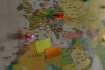 Close-up of sticky notes and board pin attached on world map — Stock Photo