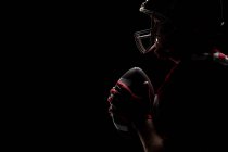 Vista laterale del giocatore di football americano in piedi con casco da rugby e palla — Foto stock