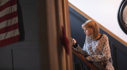 Schöne Frau benutzt Handy im Treppenhaus zu Hause — Stockfoto