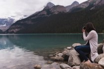Вид збоку жінки, що натискає фотографії з камерою біля озера — стокове фото