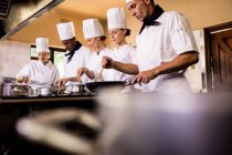 Group of chef preparing food in kitchen — Stock Photo