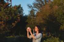 Beautiful woman clicking photos with mobile phone near riverside — Stock Photo