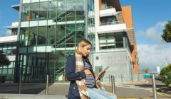 Mujer embarazada usando tableta digital en la ciudad en un día soleado - foto de stock