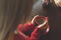 Жінка тримає чашку кави на столі в кафе — стокове фото