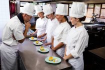 Head chef inspecting dessert plates in restaurant — Stock Photo
