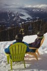 Couple sitting on chair at mountain during winter — Stock Photo