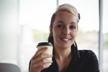 Portrait de femme tenant une tasse de café jetable dans un café — Photo de stock