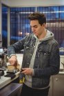 Mann presst Kaffee mit Stampfer in Portafilter in Café — Stockfoto
