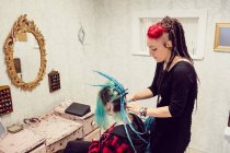 Esteticista peinado clientes cabello en dreadlocks tienda - foto de stock