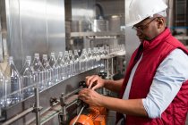 Confident male worker operating machine in juice factory — Stock Photo