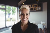 Portrait of smiling waitress standing in cafe — Stock Photo